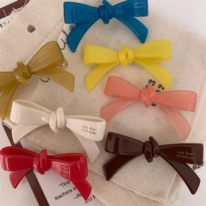 Barrettes à cheveux en acétate coloré avec lettrage fait main sur un sac en toile