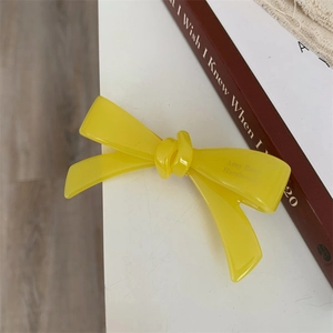 Vue détaillée d'une pince à cheveux nœud jaune avec inscription Amy Bear Handmade