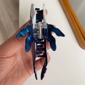 Detail view of the whale-shaped hair claw showing the blue acetate texture and inner spring