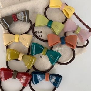 Flat lay of colorful acetate bow hair ties in a ten-piece set on a canvas bag