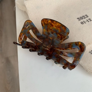 Detail of premium marble texture acetate hair claw with golden Amy Bear handmade branding