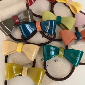 Close-up of handmade acetate bow hair ties in assorted Morandi colors with elastic bands