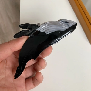 Detailed close-up of a blue whale shaped hair claw clip in black and white acetate finish