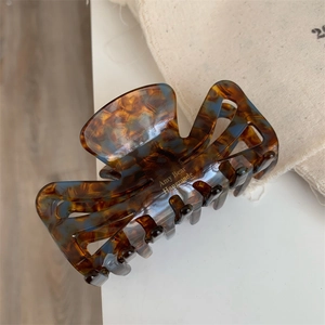Detailed shot of amber acetate hair claw clip with golden handmade lettering logo