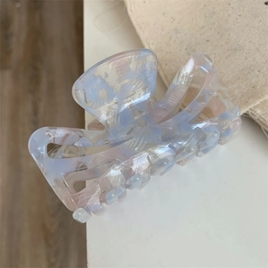 Macro detail of pink and blue marble acetate hair claw clip with pearlescent finish