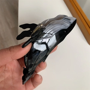 Detail showing high-gloss black and white whale-shaped acetate hair claw clip