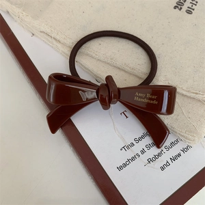 Détail d'un chouchou noeud marron foncé avec texte doré Amy Bear Handmade sur tissu