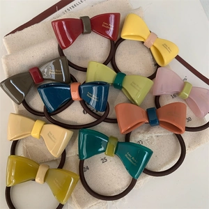 Detail view of colorful resin bow hair ties with handmade logo text in various colors