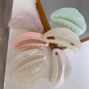 Detail of crescent acetate hair claws in pastel shades with pearl finish and branding