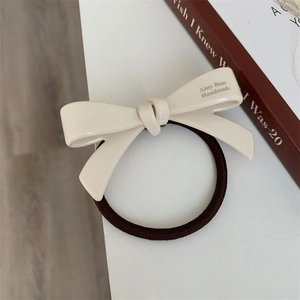 Détail d'un chouchou à nœud crème avec inscription faite main sur un bureau épuré