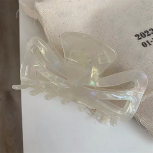 Macro detail of creamy pearlescent acetate hair claw clip on a rustic linen background