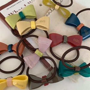 Flat lay of colorful acrylic bow hair ties with Amy Bear Handmade text on linen fabric
