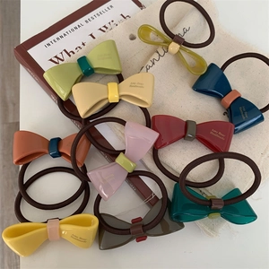 Flat lay of colorful acrylic bow hair ties on a book with high-elastic hair bands