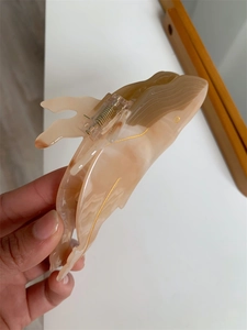 Detail showing marble-textured whale hair claw clip with golden accent and acetate finish