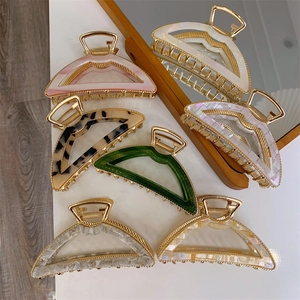 Close-up of assorted claw clips with gold metal frames and colorful acetate patterns