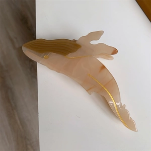 Detail view of the elegant whale-shaped acetate hair claw with gold outline and marble texture