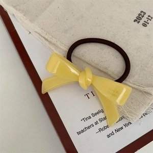 Vue détaillée d'un chouchou à nœud en acétate jaune sur lin et papier vintage