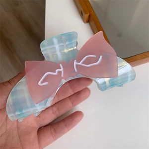 Detailansicht einer großen blauen Haarklammer aus Acetat mit rosa Schleife in der Hand