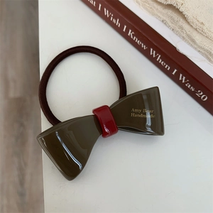 Detail of olive green acetate bow hair tie with Amy Bear gold lettering and elastic band