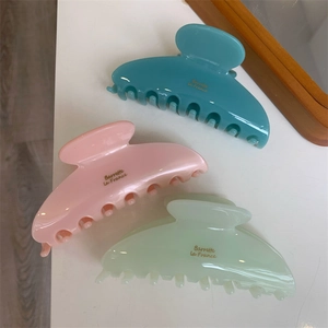 Détail de trois grandes pinces à cheveux pastel en bleu, rose et vert avec lettrage doré