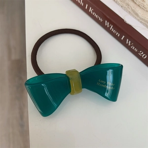 Detail of green acetic acid bow hair tie with Amy Bear Handmade gold letter print