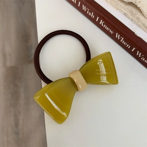 Detail of avocado green resin bow hair tie with high-elastic brown woven band