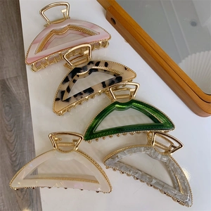 Detailed close-up of arched metal and acetate hair claws in five elegant marble finishes