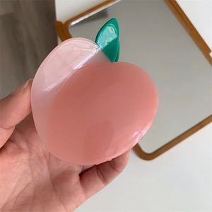 Détail de la pince à cheveux en acétate en forme de pêche rose avec feuille verte