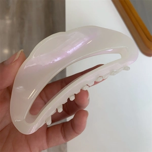 Macro detail of crescent acetate hair claw clip showing pearlescent texture and robust teeth