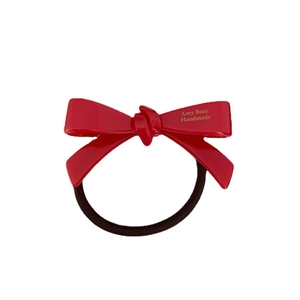 Élastique à cheveux avec nœud en acétate rouge brillant et inscription dorée élégante