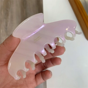 Macro detail of large acetate hair claw clip with pearlescent finish and gold lettering