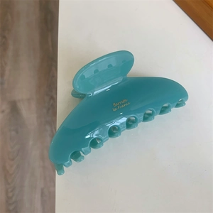Gros plan détaillé d'une pince à cheveux bleu lac brillant avec inscription dorée