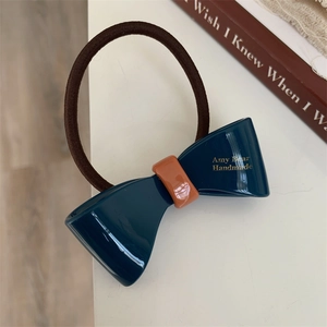 Detailed macro view of the navy blue ribbon bow hair tie with golden handmade lettering