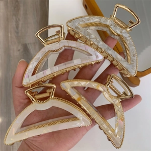 Detail of four large acetate hair claws with gold-toned alloy frames and pearlescent finish