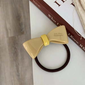 Detail of a handmade acetate bow hair tie with high elastic band and stylish letter print