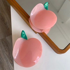 Détail de la pince à cheveux en forme de pêche rose en acétate avec feuilles vertes