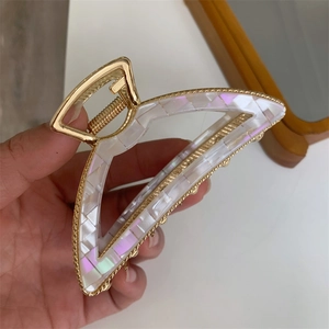 Macro detail of French style golden metal hair claw clip with iridescent white acetate
