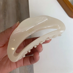 Detailed macro view of the gold handmade lettering on the cream acetate hair claw clip