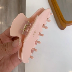 Detail shot of light pink acetate hair claw clip with golden Barrette la France text