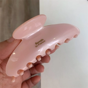 Détail d'une pince à cheveux en acétate rose avec lettrage doré Barrette la France