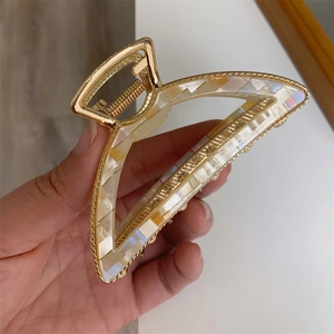 Close-up of a French style metallic hair claw clip with creamy shell texture finish