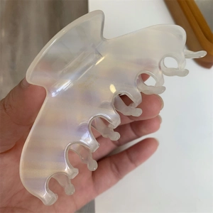 Macro detail of a large translucent pearlescent hair claw with fine letter logo