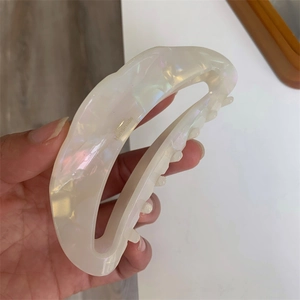 Detail view of iridescent acetate hair claw clip with handmade engraving and sleek teeth