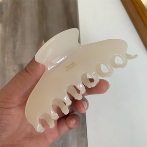 Close-up of a cream acetate hair claw clip with yellow Barrette La France lettering