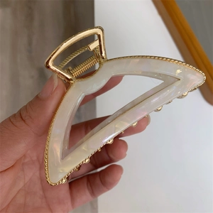 Detail of golden triangular hair claw with shimmering white mother of pearl inlay texture