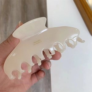 Detail showing cream-colored resin hair claw clip with Barrette La France lettering