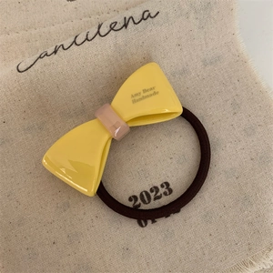 Macro shot of yellow acetic acid bow hair tie with pink center and elastic band detail