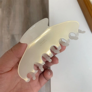 Detail view of a large cream-colored acetate hair claw with Barrette La France lettering