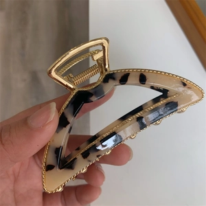 Detail of a gold metal hair claw clip with cream tortoiseshell acetate inlay