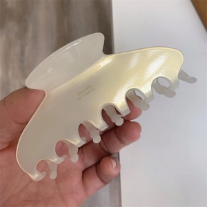 Detail of pearl white acetate hair claw clip featuring Barrette La France gold lettering